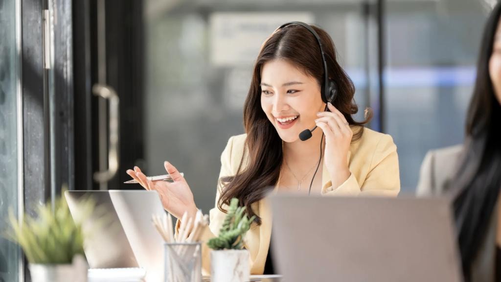 Smiling woman talking on a desk phone in an office